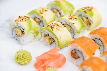 Sushi rolls on platter, bright background. Served with wasabi and ginger. Assorted Japanese sushi. Traditional food. 