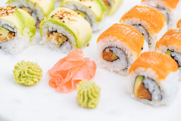 Sushi rolls on platter, bright background. Served with wasabi and ginger. Assorted Japanese sushi. Traditional food. 