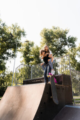 Kids girls smile and laugh and have fun together. Children with skateboard and penny boards communicate and discuss on the sports playground. Girls friendship concept.