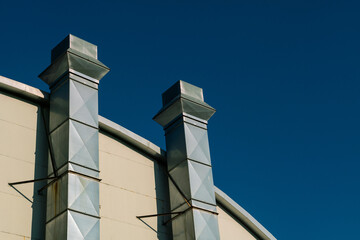 Obraz premium ventilation system building: chimney of an industrial building with smoke outlet for a heating and ventilation system, in shiny galvanized metal.