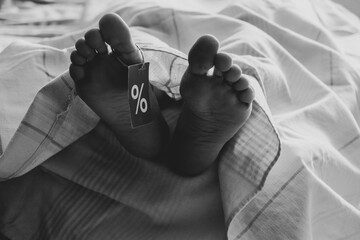 Women's legs with a tag covered with a sheet on the table, the legs of a dead person, the sale of dead people