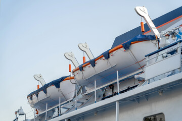 Two white lifeboats on the side of a cruise ship