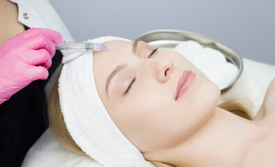 Injection in the forehead at the spa salon. The doctor's hands. Biorevitalization. Facial care from a cosmetologist