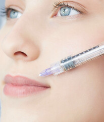 A woman with beautiful clear skin. A cosmetologist makes injections to increase the lips and...