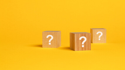 three cubes with question mark on wooden background. space for text, yellow background