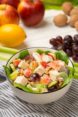 Chicken Waldorf salad of apples, celery stalks, walnuts, grapes, lettuce in a white salad bowl with ingredients on an old rustic white wooden table. Selected focus. - 523646494