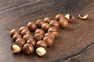 Macadamia nuts with notched shells and a few open nuts.