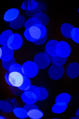 Dancing holiday bokeh lights in deep ocean blue tones overlap in a colorful design pattern