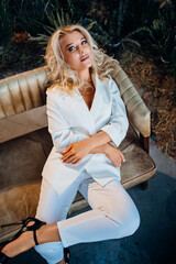 a woman in a white pantsuit on a leather sofa. cosmetics and cosmetology.