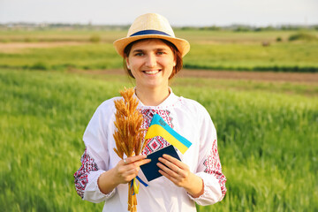 Defocus young ukrainian woman portrait. Bouquet of ripe golden spikelets of wheat tied on the...