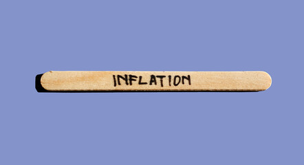 Word inflation written on wood stick isolated on pastel blue background. Inflation world economics and inflation control concept	