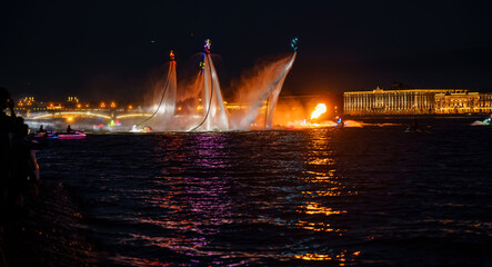 A lot of flyboarders and brightly dressed up jet skiers perform their show at a holiday in the...