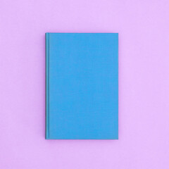 Blue hardcover vintage book on pastel purple background. Flat lay copy space