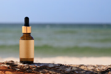 Glass bottle with essential oil cosmetic product background beach sand. Empty label, copy space. For product display, mock-up.