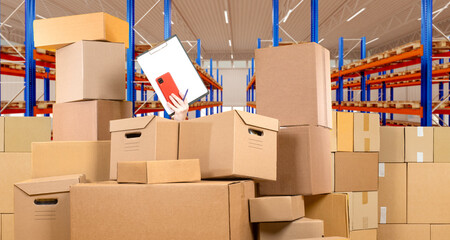 Production warehouse. Lots of cardboard boxes in stock. The man is overwhelmed with cases in the...