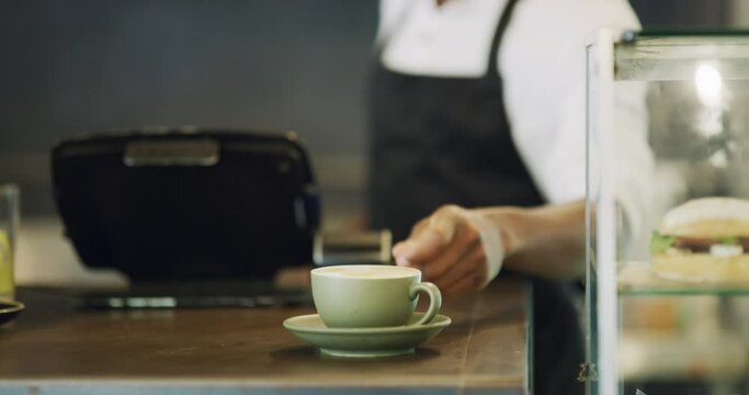 Waiter hands serving cup of coffee, tea and hot drink in a local cafe, small restaurant or bar. Closeup of man and server wearing an apron and giving warm, comforting and delicious beverage in a mug