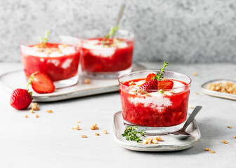 Vegetarian fruit cream dessert with strawberry puree, yoghurt and granola in glass bowls. Homemade healthy clean food concept. Copy space.