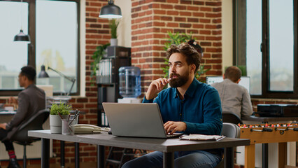 Thoughtful businessman brainstorming ideas to create report on laptop, feeling pensive and thinking about good decision to create presentation. Stressed worker pondering company solution.