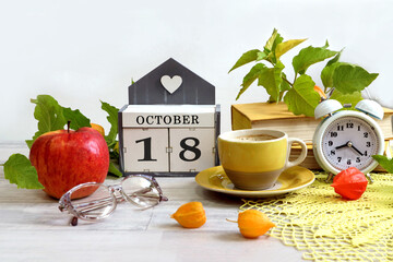 Calendar for October 18: a decorative house with the numbers 18, the name of the month October in English, a red apple, glasses, physalis branches, a stack of books, a cup of coffee, a clock