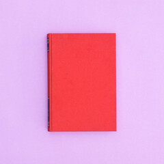 Red hardcover vintage book on pastel purple background. Flat lay copy space