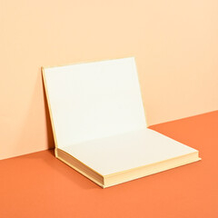 Creative backgorund with open hardcover book on two shade orange background. Flat lay copy space