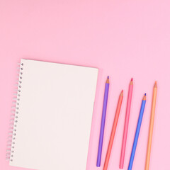 Pastel wooden pencils with open notebook copy space on pastel pink background. Flat lay Back to shool