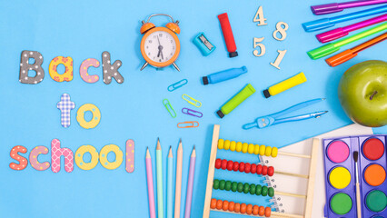 Back to school text with school supplies on pastel pink background. Flat lay