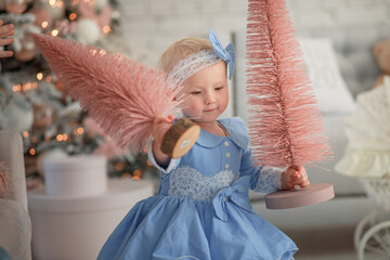 Beautiful girl holding Christmas tree. Happy baby celebrates Christmas and New Year.