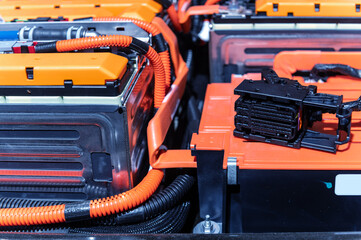 Electric car battery with power connections closeup. Blue toned. EV car battery at maintenance. High voltage power connector closeup.