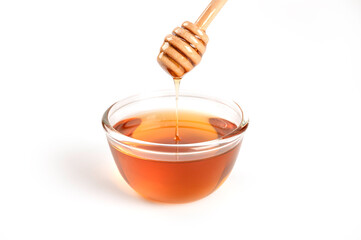 Glass bowl of honey with honey dipper on white background.