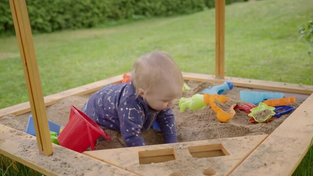 Toddler Boy Playing With Multi Colored Toys In Sand At Backyard - Jablonec nad Nisou, Czechia