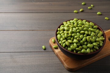 Bowl of delicious edamame beans on wooden table, space for text