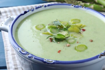 Delicious asparagus soup in bowl on table, closeup