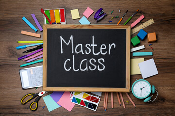 Blackboard with words Master Class surrounded by different stationery on wooden table, flat lay