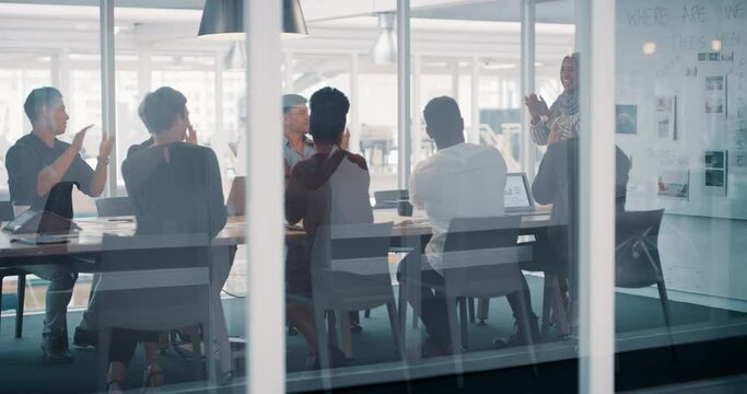 Happy, celebrating and clapping corporate team after a successful business planning meeting. Diverse group of businesspeople sitting and listening to a muslim manager in the boardroom at the office.