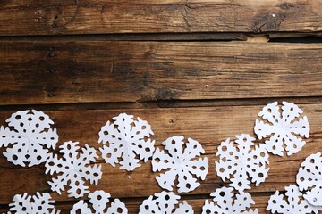 Many paper snowflakes on wooden background, flat lay. Space for text