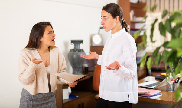 Irritated woman boss scolding stressed manager for incompetence with documents in office