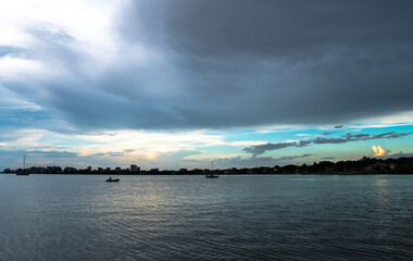 Fototapeta premium Dusk to Dawn over Sarasota Bay, Florida. Colorful stormy skies with Longboat Key and Sarasota downtown skyline in the distance. Light and colors.