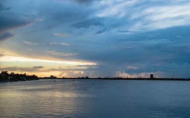 Fototapeta na wymiar Dusk to Dawn over Sarasota Bay, Florida. Colorful stormy skies with Longboat Key and Sarasota downtown skyline in the distance. Light and colors.