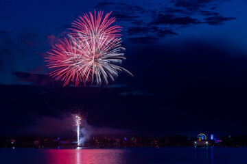 Fireworks celebration with reflections across the river with a town in the background