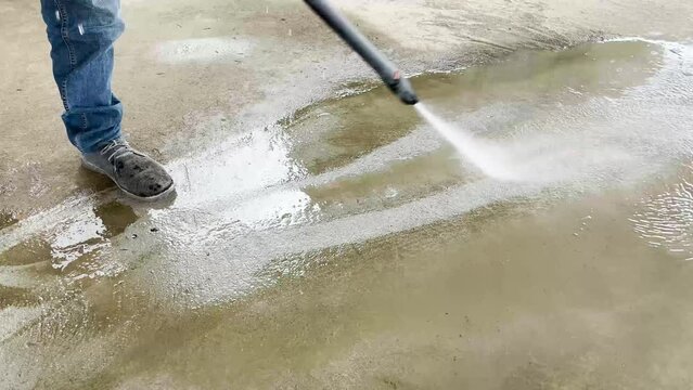 Man using pressure washer to clean the floor. Cleaning the floor with pressurized water. Manual pressure washer in operation