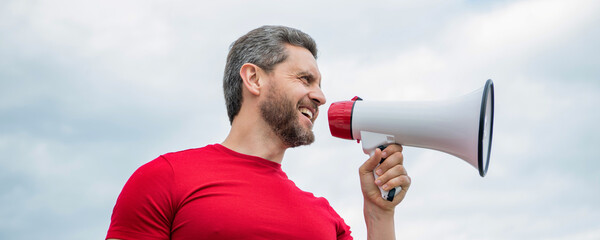 man advertiser in red shirt shout in loudspeaker on sky background - obrazy, fototapety, plakaty