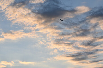 Fototapeta na wymiar Avion volando en altura en el atardecer con nubes muy coloridas