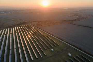 Aerial view of large sustainable electrical power plant with rows of solar photovoltaic panels for producing clean electric energy in evening. Concept of renewable electricity with zero emission