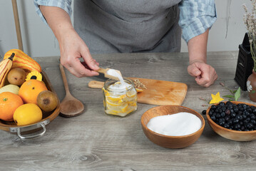 woman's hands canning lemon. pour sugar into  jar of lemon.