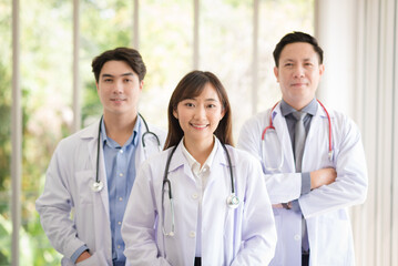 Group of Asian doctors team portrait standing with colleagues in background.