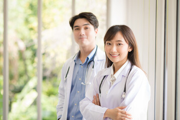 Group of Asian doctors team portrait standing with colleagues in background.