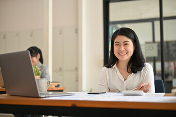 Fototapeta na wymiar Attractive and happy young Asian businesswoman at her office desk.
