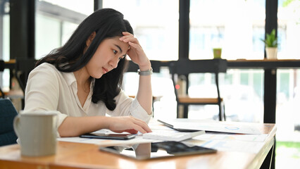 Stressed and thoughtful Asian businesswoman pensive thinking about her sales report.