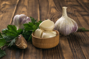 Peeled garlic cloves and whole garlic on a wooden table.